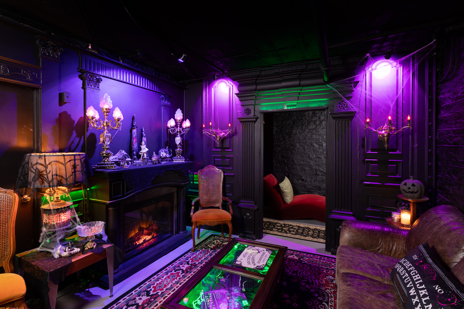 Gertrude's Cistern, the haunted-theme basement lounge at 300 Clifton, glowing purple with candelabras, a fireplace and a velvet chaise